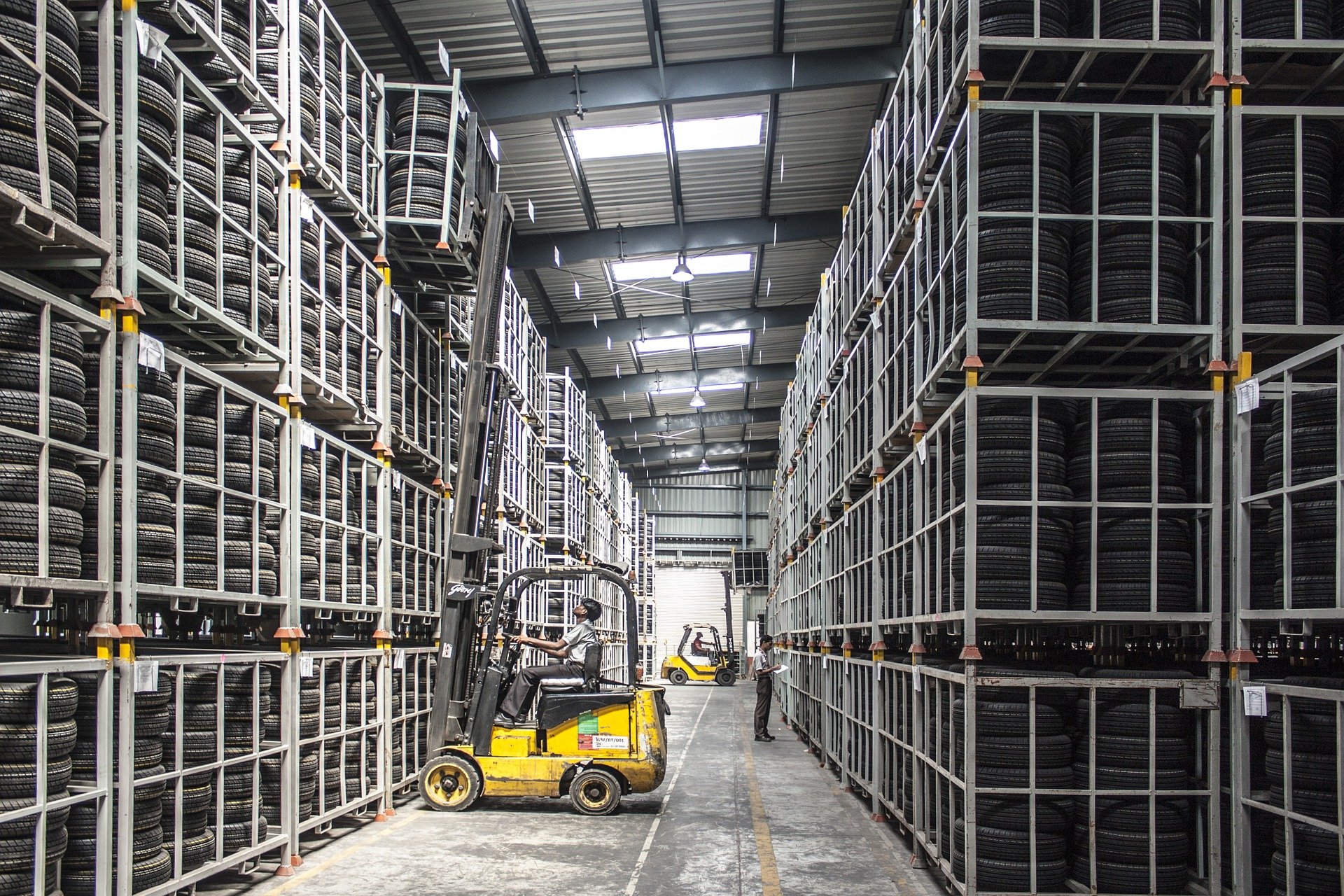 Forklift operator moving tires in large warehouse